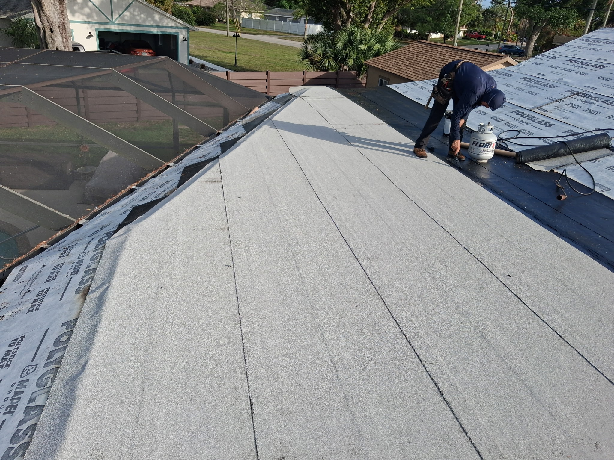 Crew torching modified bitumen membrane on a low-slope residential roof in Sarasota